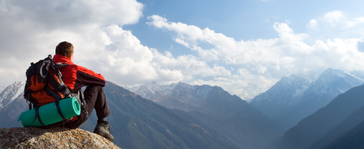 man sitting on a mountain taking in the beautiful view