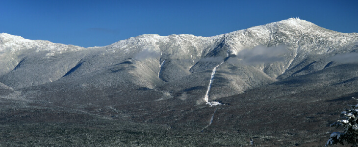 snowy mountain scape with blue sky and green trees below consumer claims